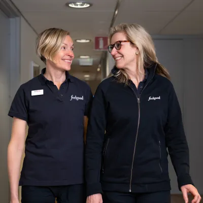 Två kvinnor i Feelgood-kläder går i korridor