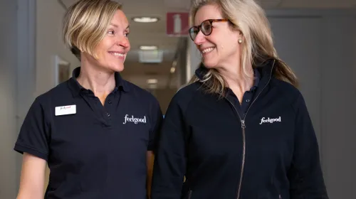 Två kvinnor i Feelgood-kläder går i korridor